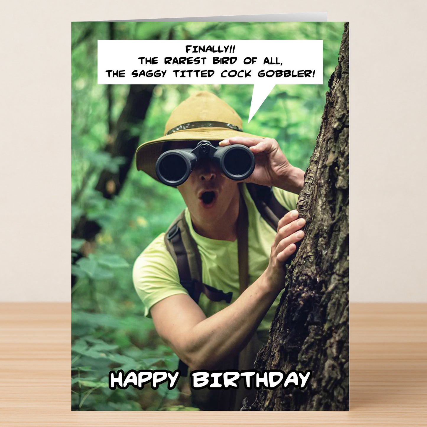 Someone in a forest wearing a hat and looking through binoculars with a funny speech bubble and “Happy Birthday” text—Gobbler, the rude birthday card by Twisted Gifts, perfect for adventure lovers who appreciate humor.