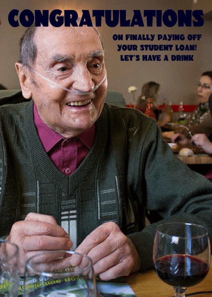 A man is sitting at a table celebrating his debt-free moment with the Twisted Gifts Student Loan Funny Congratulations Card.