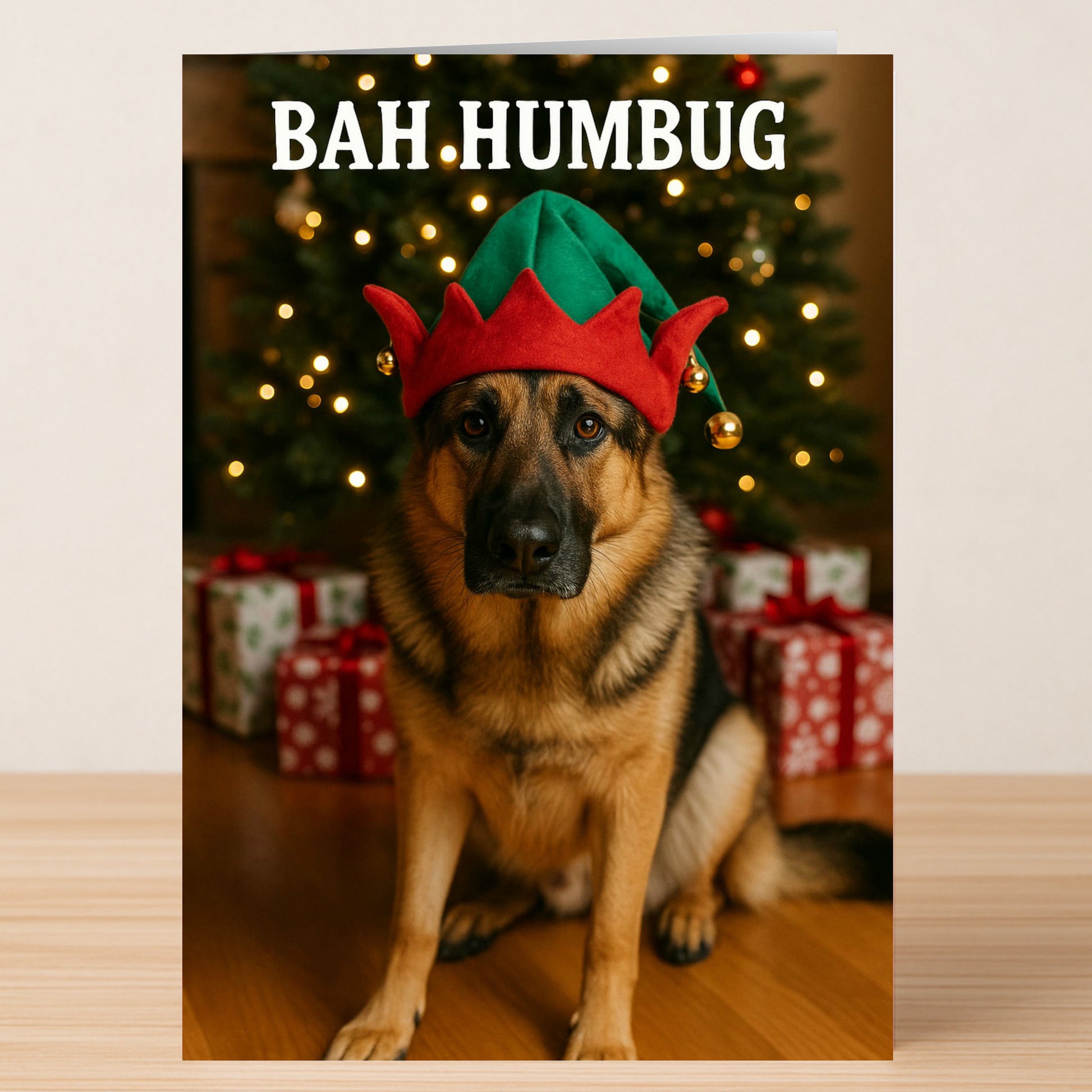 The Bah Humbug Christmas Card from Twisted Gifts features a German Shepherd in a red and green elf hat by a tree and presents, with "BAH HUMBUG" above—a fun, quirky card for dog lovers this holiday season.