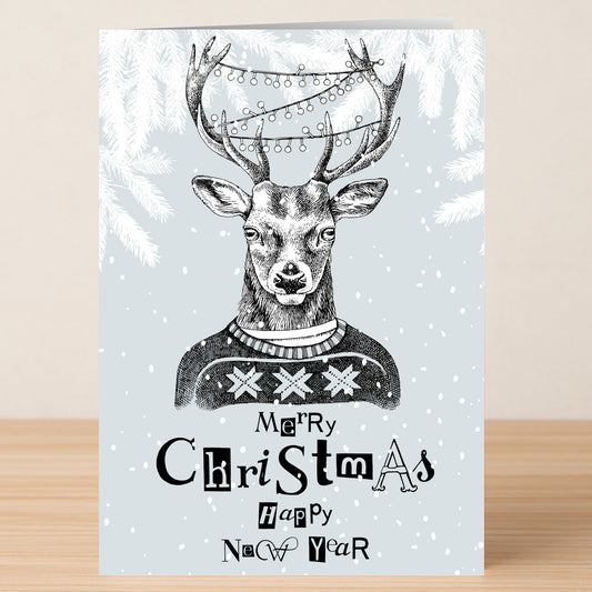 Send festive wishes with Twisted Gifts' Funky Reindeer Christmas Card—featuring an illustrated reindeer in a cozy sweater with string lights on its antlers, snowy branches, and "Merry Christmas Happy New Year" text.