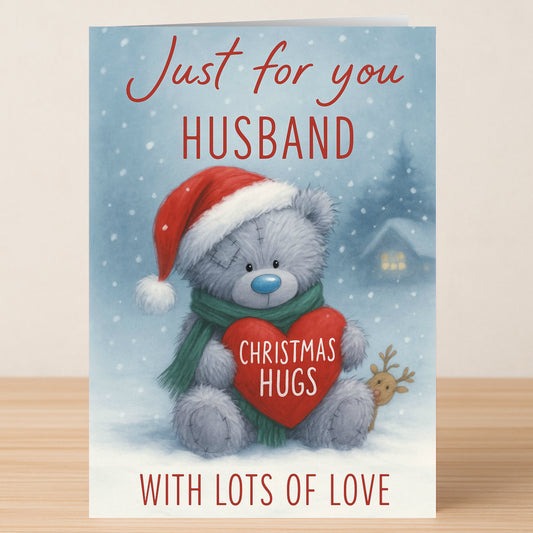 The Twisted Gifts Husband Bear Christmas Card features a gray teddy bear in a Santa hat and green scarf, holding a heart labeled "Christmas Hugs," with the message: "Just for you Husband, with lots of love.