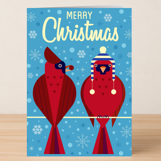 The Twisted Gifts Birds Christmas Card features two red cardinals on a wire—one in a blue and white winter hat—against a blue snowflake background with “Merry Christmas” text, perfect for festive holiday greetings.