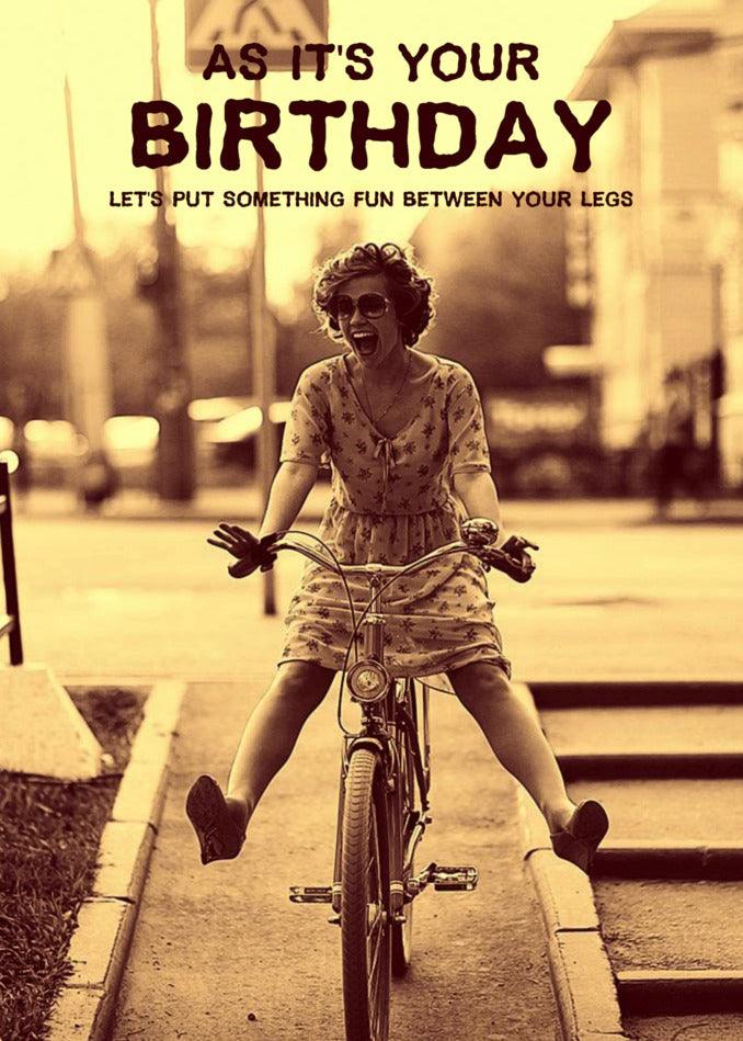 A woman riding a bike with a Twisted Gifts Fun Rude Birthday Card.