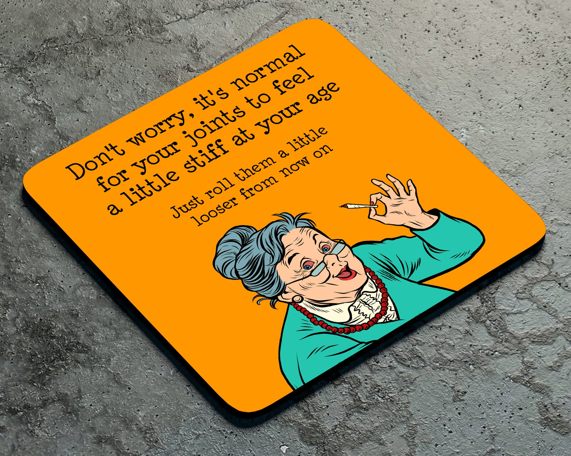 The Stiff Joints Coaster by Twisted Gifts features a witty elderly woman making an "OK" sign, humorously advising to roll joints looser with age—an ideal funny coaster or cheeky gift for friends who love a good laugh.