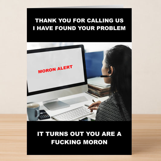 A woman in a headset sits at her desk, looking at a screen showing "MORON ALERT"—a funny scene featured on the Moron Alert Insulting Greeting Card by Twisted Gifts, ideal for anyone who enjoys sarcastic and witty messages.
