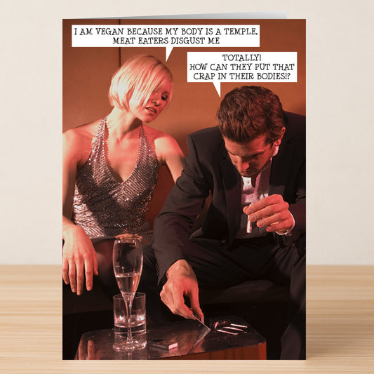 A woman and man exchange witty vegan jokes at a table, poking fun at meat lovers—making Twisted Gifts’ Meat Eaters Funny Greeting Card the perfect pick for anyone who loves humor and unique cards.