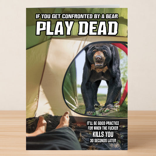 The Play Dead Funny Greeting Card by Twisted Gifts features a person inside a tent with a bear outside, visible through the tent flap. Bold text reads, "If you get confronted by a bear, PLAY DEAD." A clever and humorous card for outdoor lovers.