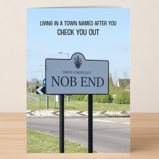 The Twisted Gifts Nob End Funny Greeting Card features a "Drive Carefully NOB END" road sign and clever humor: "Living in a town named after you, check you out." Printed on premium materials for a memorable touch.