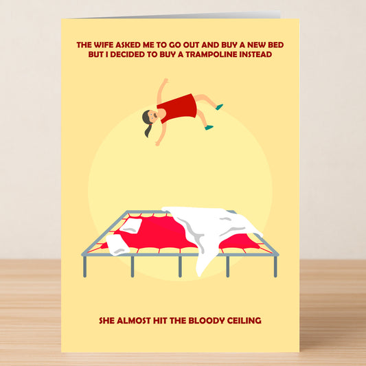 The Trampoline Funny Greeting Card from Twisted Gifts shows a cartoon woman bouncing on bed sheets, humorously suggesting a trampoline adds extra spring to her step over an ordinary bed.