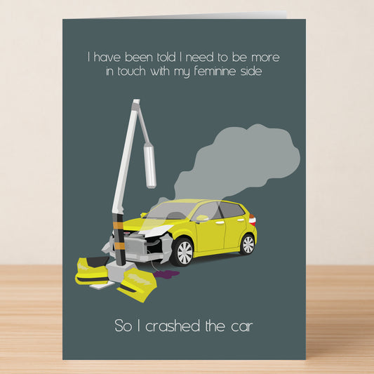 The Feminine Side Funny Greeting Card by Twisted Gifts features a yellow car crashed into a pole with smoke, plus the witty message: "I have been told I need to be more in touch with my feminine side. So I crashed the car." Printed on high-quality materials.