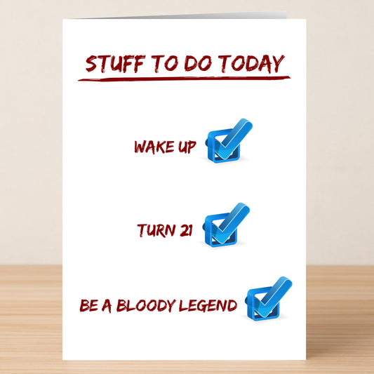 The Twisted Gifts "21 - Stuff To Do 21 Funny Birthday Card" humorously lists tasks like waking up, turning 21, and being a legend—perfect for celebrating a 21st birthday. The card is shown standing on a wooden surface.