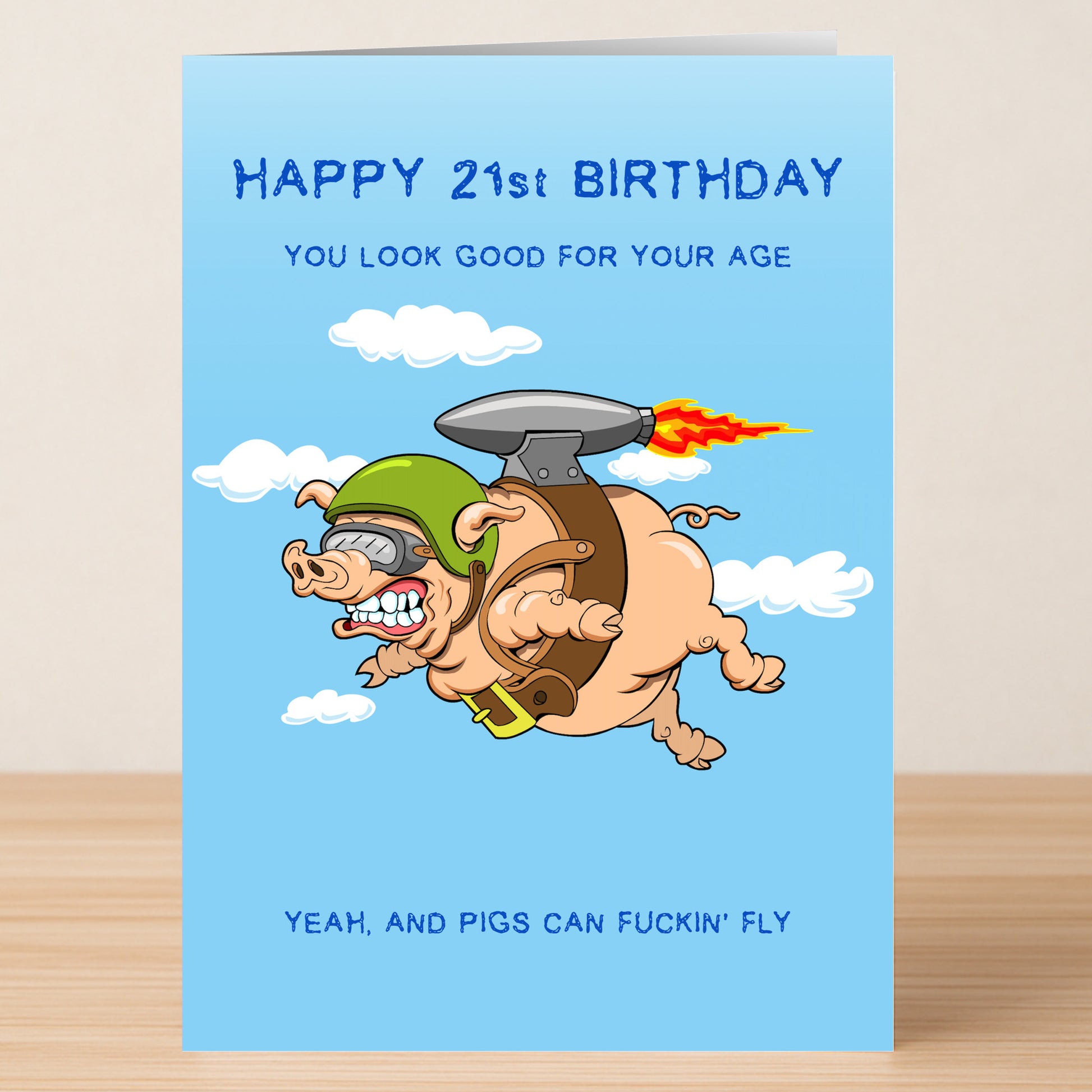 The Twisted Gifts "21 - Pigs Can Fly 21 Insulting Birthday Card" features a cartoon pig in a jetpack and helmet soaring among clouds with the cheeky message: "Happy 21st Birthday, you look good for your age—yeah, and Pigs Can Fly.
