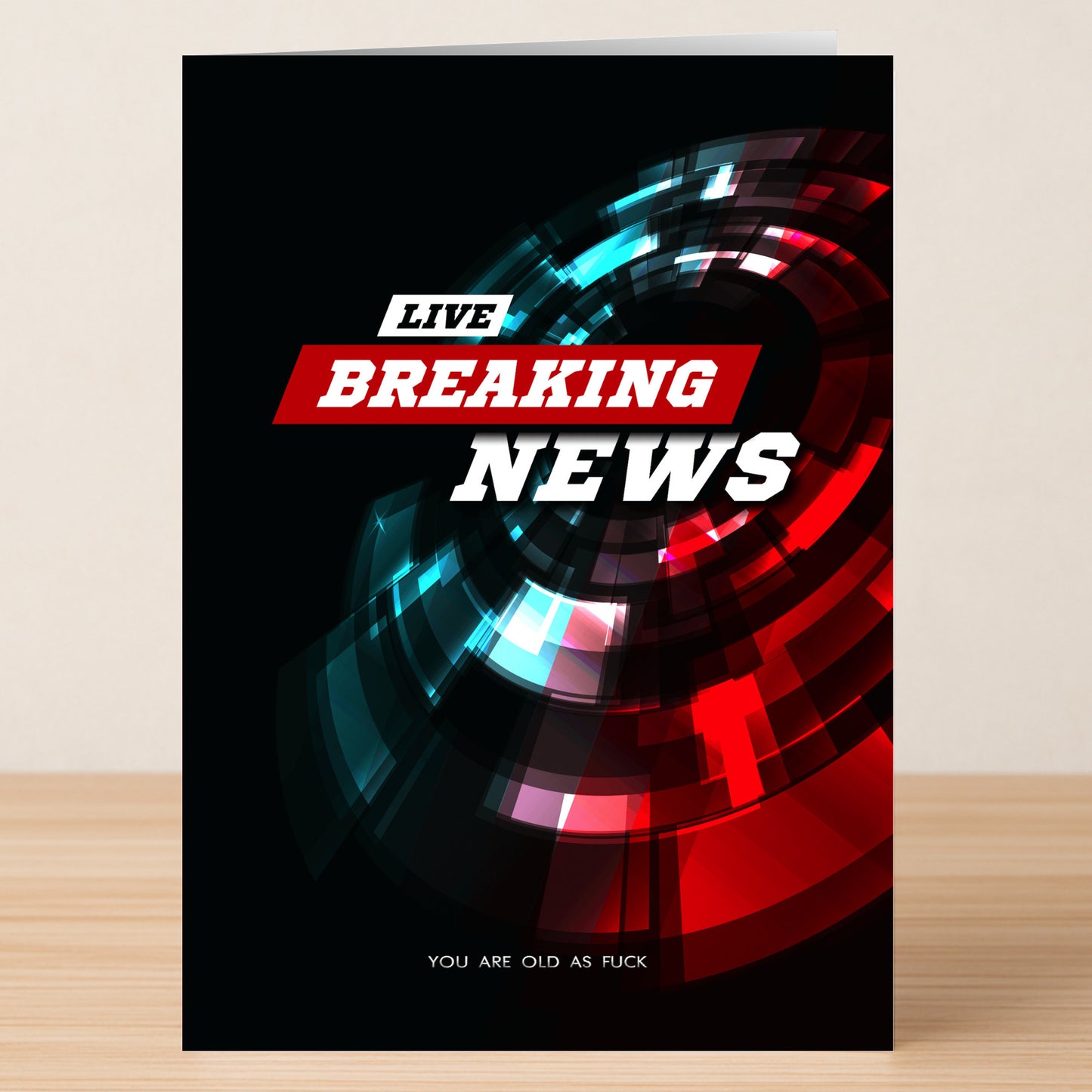 The Breaking News Insulting Birthday Card by Twisted Gifts features a bold "LIVE BREAKING NEWS" headline over a red and blue abstract background, ending with the funny message "YOU ARE OLD AS FUCK"—an ideal insulting birthday card.