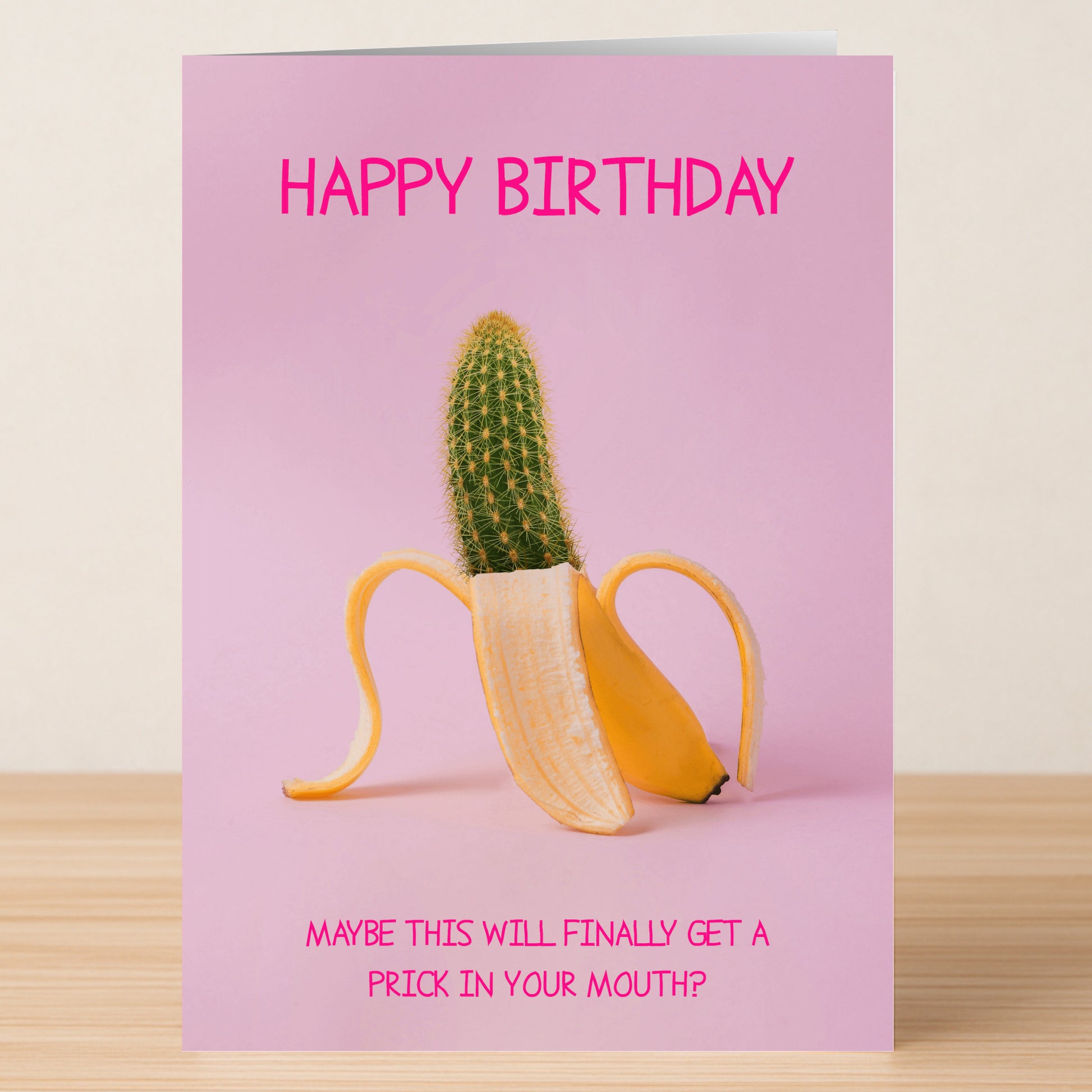 The In Your Mouth Funny Birthday Card by Twisted Gifts features a peeled banana showing a cactus inside, set on a pink background, with the message: "HAPPY BIRTHDAY" and "MAYBE THIS WILL FINALLY GET A PRICK IN YOUR MOUTH?.