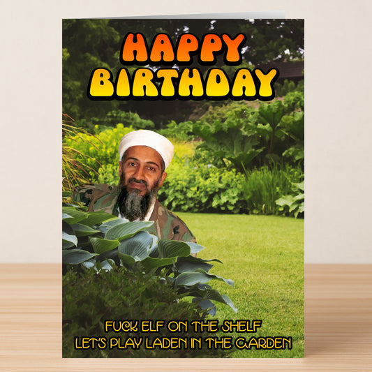 The Laden Garden Funny Birthday Card by Twisted Gifts features bold "Happy Birthday" text and a cheeky man hiding in a garden with the caption, "Fuck elf on the shelf, let's play Laden in the garden." Ideal for a memorable birthday.