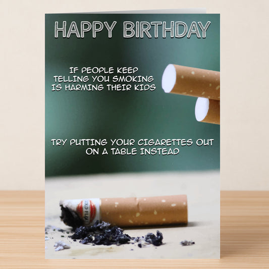 The Cigarettes Funny Birthday Card by Twisted Gifts features two cigarettes with ashes and the text: "If people say smoking harms their kids, try putting your cigarettes out on a table instead.