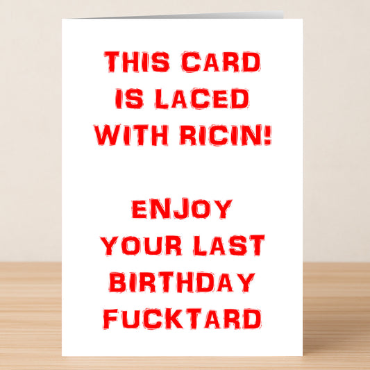 The Ricin Funny Birthday Card by Twisted Gifts features bold red text on a wooden background: "THIS CARD IS LACED WITH RICIN! ENJOY YOUR LAST BIRTHDAY FUCKTARD." A perfect card for dark humor fans on their birthday.