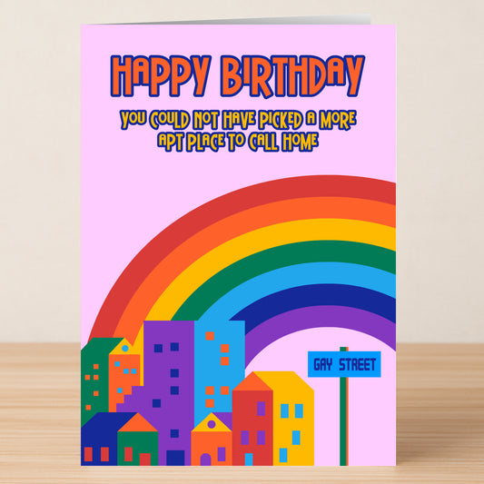 The Gay Street Funny Birthday Card by Twisted Gifts features colorful buildings, a rainbow, and a “Gay Street” sign. The card reads: "Happy Birthday. You could not have picked a more apt place to call home.