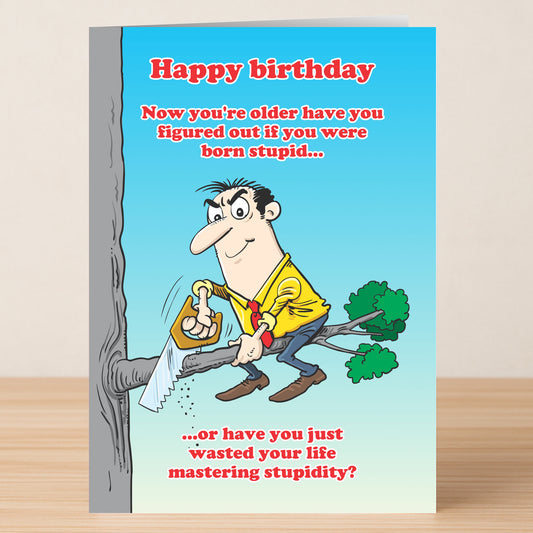 The Master Stupidity Funny Birthday Card by Twisted Gifts features a cartoon man sawing off his own branch and the witty message: "Happy birthday. Now you’re older, have you figured out if you were born stupid or mastered stupidity?.