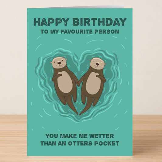 Twisted Gifts' Otters Pocket Rude Birthday Card features two cartoon otters holding hands in a heart, with the message: “Happy Birthday to my favourite person. You make me wetter than an otter’s pocket.” Ideal for humor lovers!.