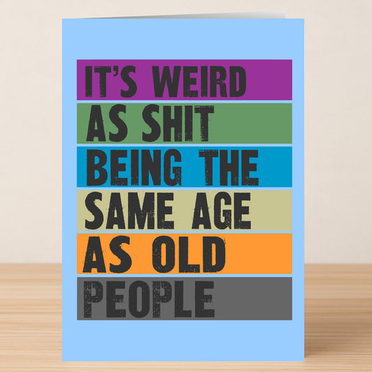The "Weird, Funny Birthday Card" by Twisted Gifts features bold, colorful text: "IT'S WEIRD AS SHIT BEING THE SAME AGE AS OLD PEOPLE," shown on a wooden surface.