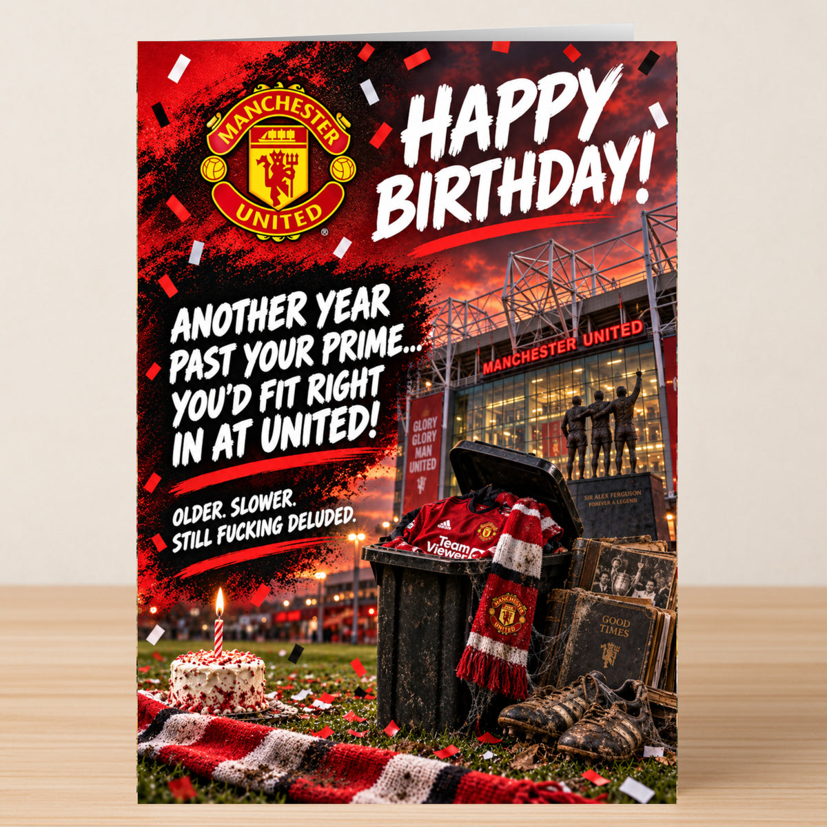 A Twisted Gifts Man United – Funny Birthday Card showing the Manchester United crest, a stadium, and a trash bin filled with a jersey, scarf, and books under the text “Happy Birthday!...”