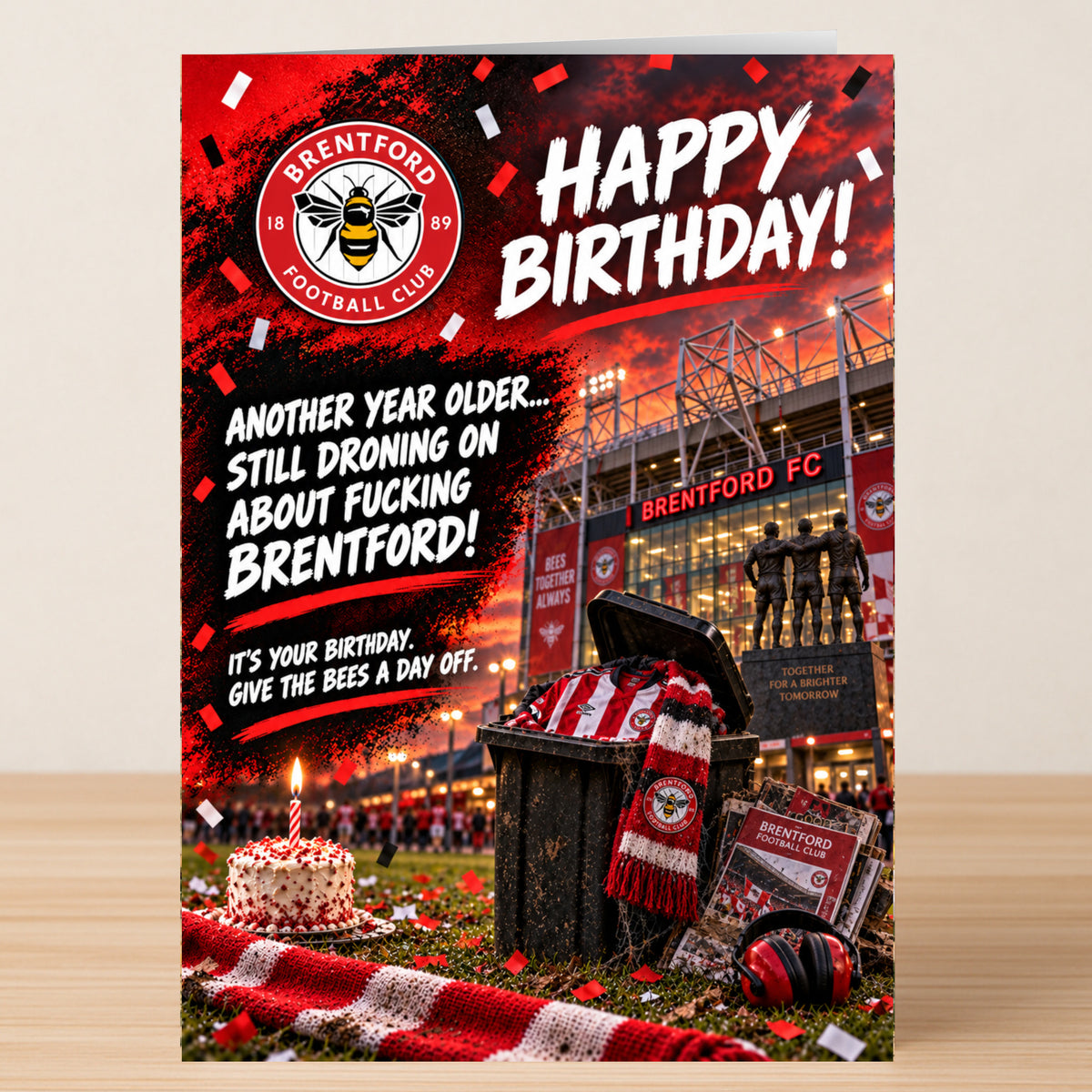 Twisted Gifts Brentford – Funny Birthday Card showing a stadium backdrop, a trash can filled with a team jersey, scarf, and program, a birthday cake, and the text: “Happy Birthday! Another year older...”
