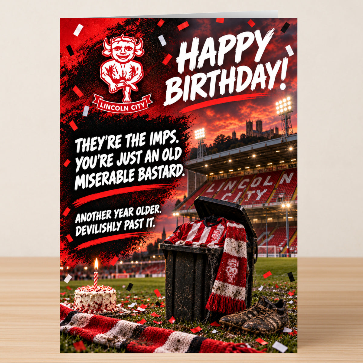 Lincoln City – Funny Birthday Card featuring a stadium background, a trash can with a team jersey and scarf, and the text: “Happy Birthday! They’re the imps. You’re just an old miserable bastard.”