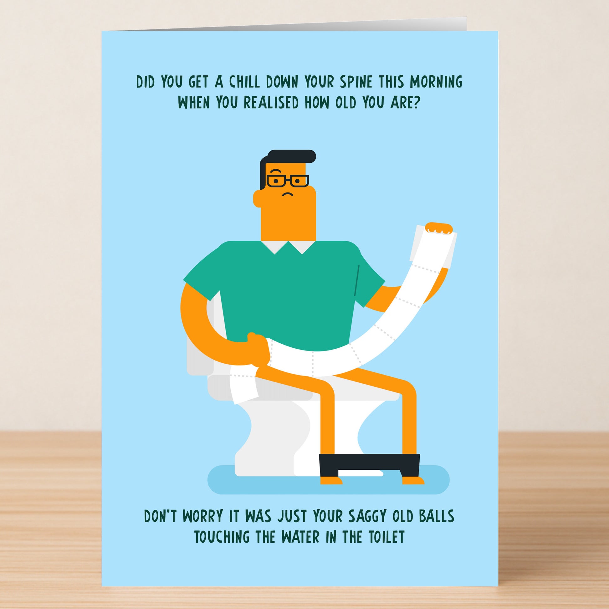 Twisted Gifts' Toilet Insulting Birthday Card features a witty illustration of a man with glasses on a toilet, holding a long roll of toilet paper, with playful humor about aging above and below the image.