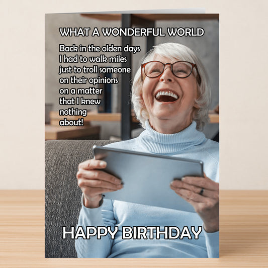 An elderly woman with white hair and glasses laughs while holding a tablet; the Twisted Gifts Wonderful World Funny Birthday Card features a witty internet trolling joke as birthday text above and below her.