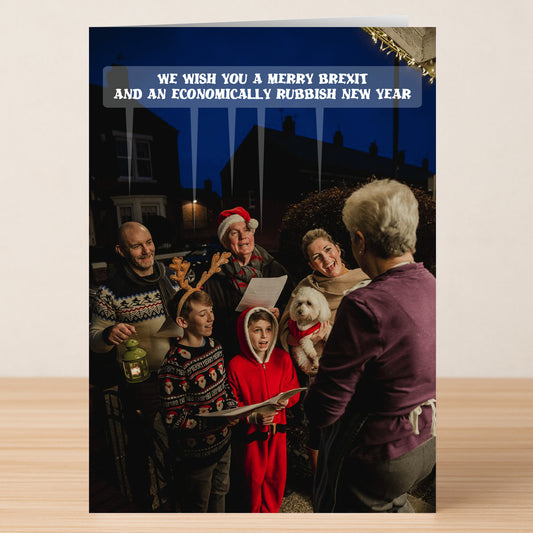 The Merry Brexit Funny Christmas Card by Twisted Gifts features festively dressed carolers singing outside a house with the caption, "We wish you a merry Brexit and an economically rubbish new year." Perfect for fans of Brexit humor.