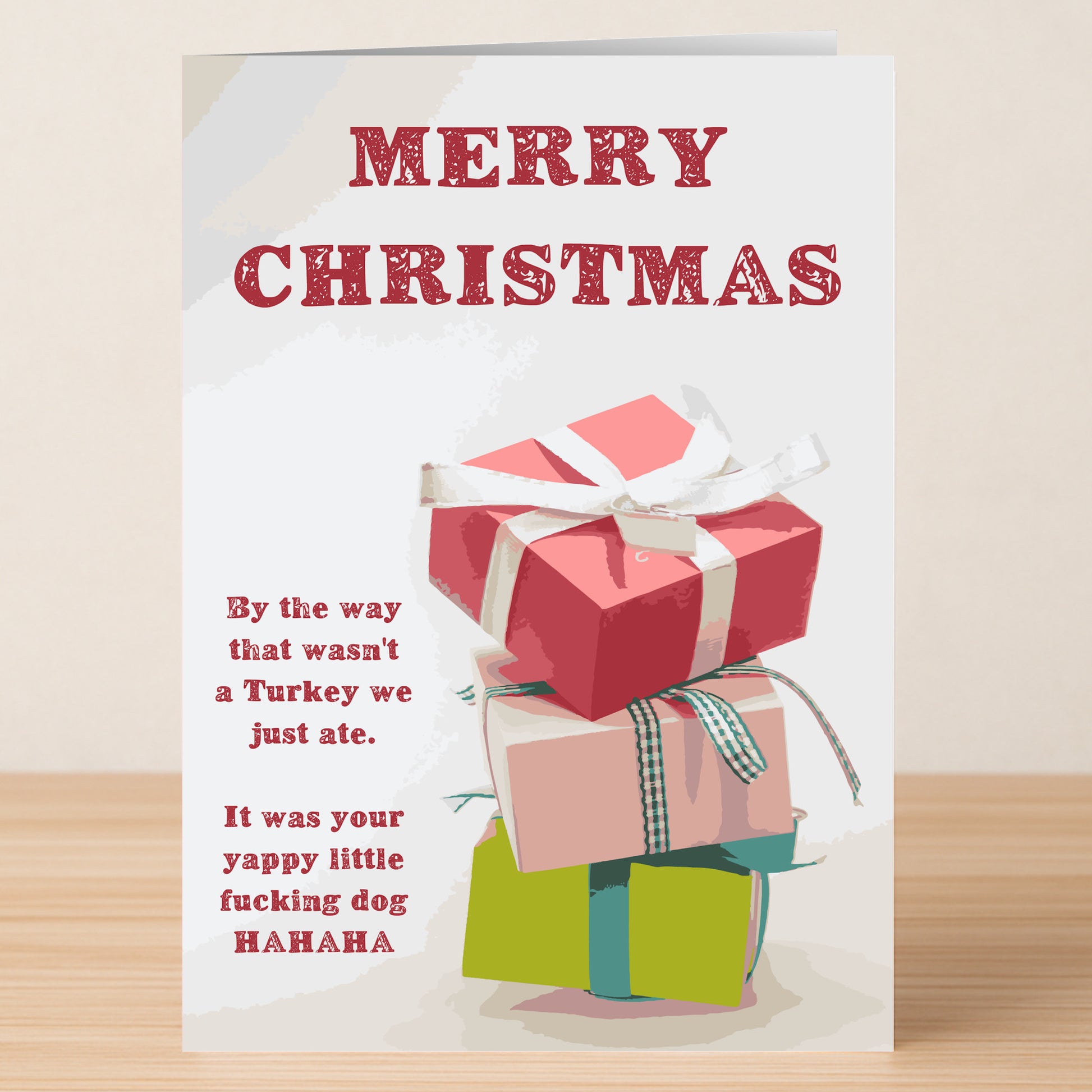 The Wasn't A Turkey, Was A Dog Funny Christmas Card by Twisted Gifts features three stacked gifts and the message: "Merry Christmas. By the way that wasn't a Turkey we just ate. It was your yappy little dog HAHAHA.