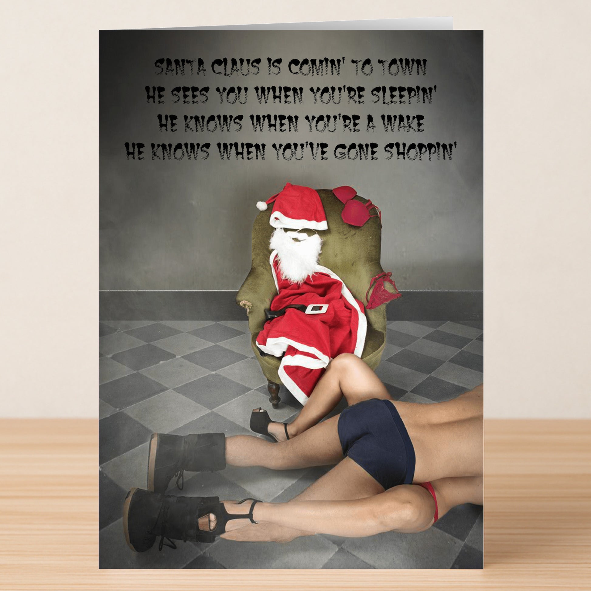 A Twisted Gifts Gone Shopping Rude Christmas Card features Santa seated on a chair and another figure in underwear and heels on the floor, with bold song lyrics on the wall for a humorous holiday design.