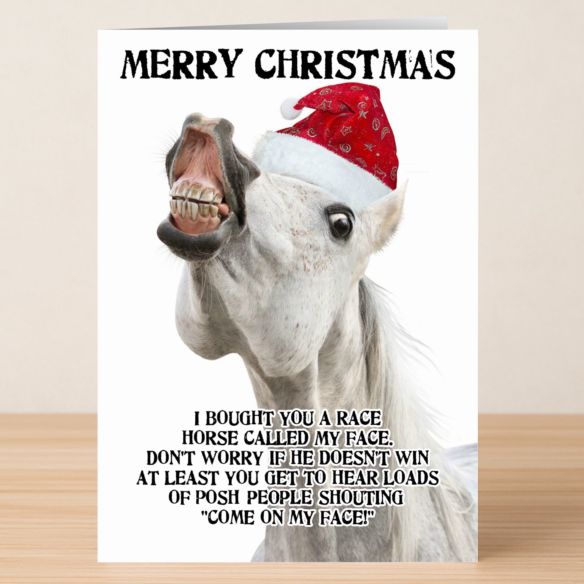 A white horse in a red Santa hat grins on the Twisted Gifts My Face Non-Rude Christmas Card, with "Merry Christmas" above and a funny message below—perfect for anyone who loves a festive laugh.