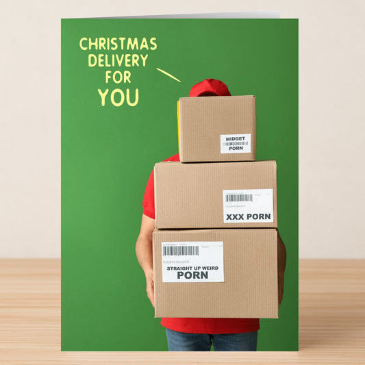 A person in red holds three stacked boxes on the Delivery Rude Christmas Card by Twisted Gifts, spreading cheeky holiday cheer with a funny message against a green background.