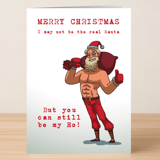 The Real Santa Funny Christmas Card by Twisted Gifts features a muscular, shirtless Santa with the message: "Merry Christmas. I may not be the Real Santa, but you can still be my Ho!" Perfect for festive laughs and holiday cheer.
