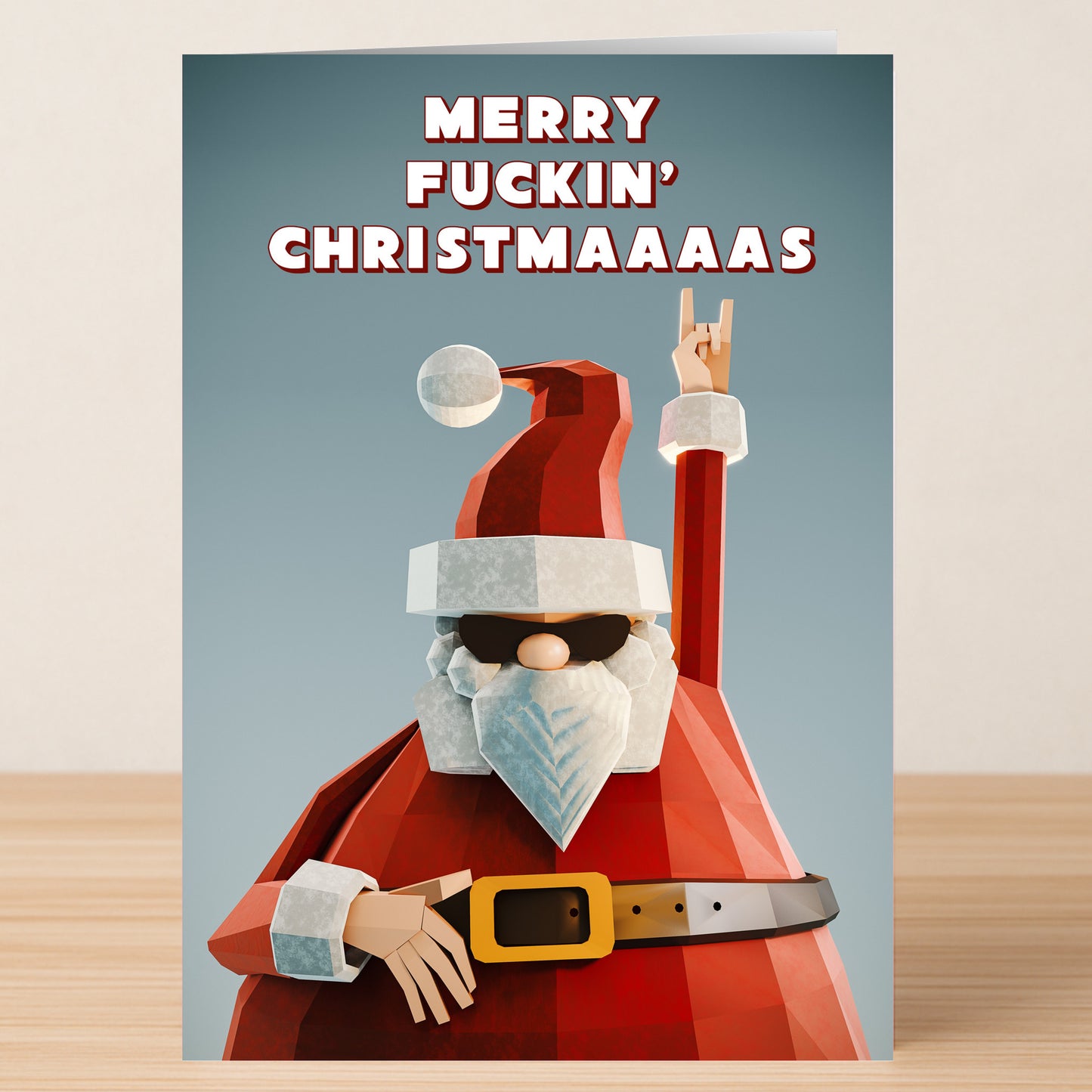 The Merry F'kn Christmas Card by Twisted Gifts features a cartoon Santa in shades flashing a "rock on" sign with the bold text "MERRY FUCKIN' CHRISTMAAAAS"—a cheeky, humorous holiday card for those who like their Christmas with attitude.