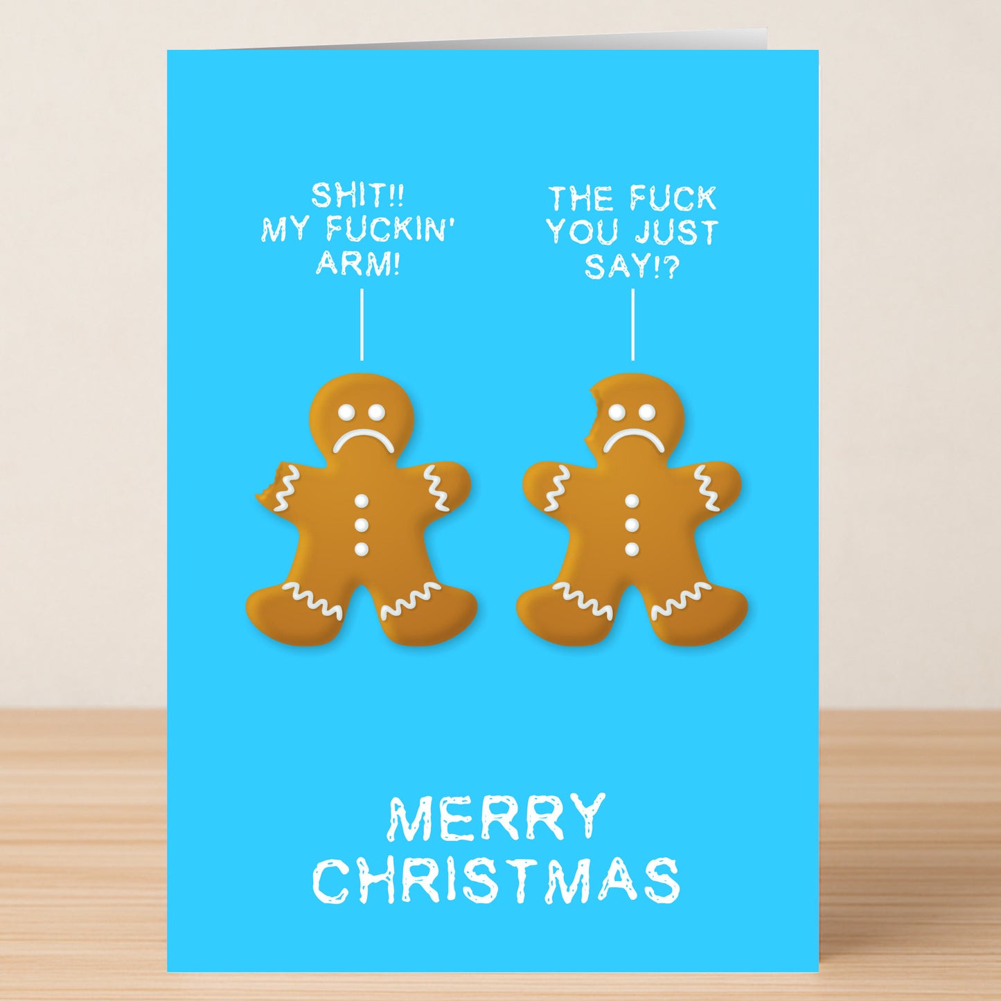 The "My Arm Christmas Card" by Twisted Gifts shows two sad gingerbread men—one missing an arm—sharing bold speech bubbles, with "Merry Christmas" below on a blue background. A cheeky, irreverent card for those who love humor!.