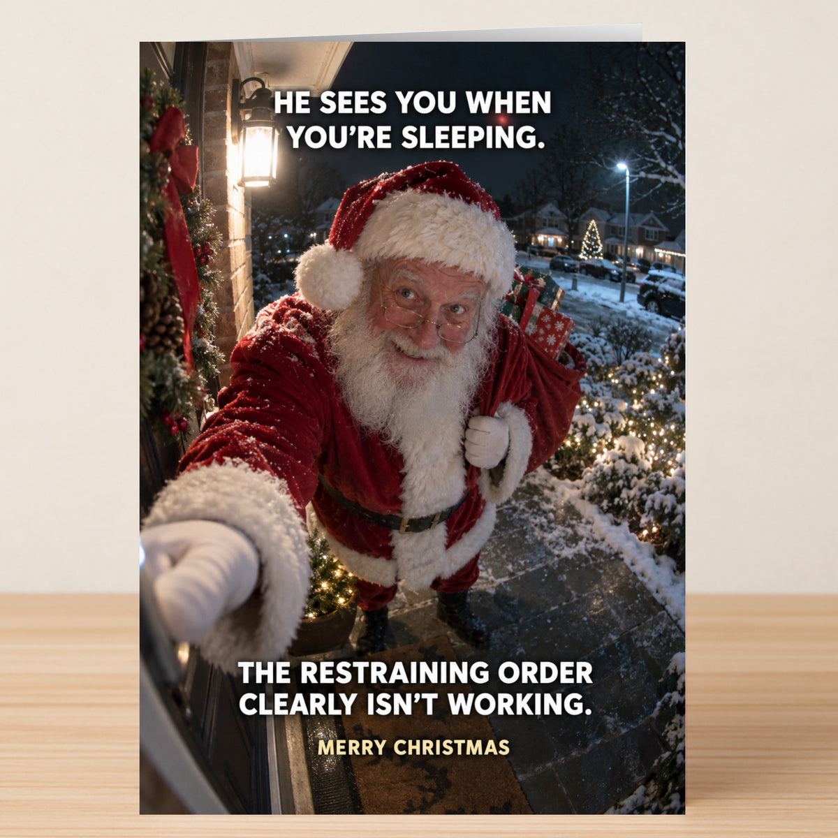 A funny Twisted Gifts Restraining Order Christmas card shows Santa at a front door with the text: “He sees you when you’re sleeping. The restraining order clearly isn’t working. Merry Christmas.”