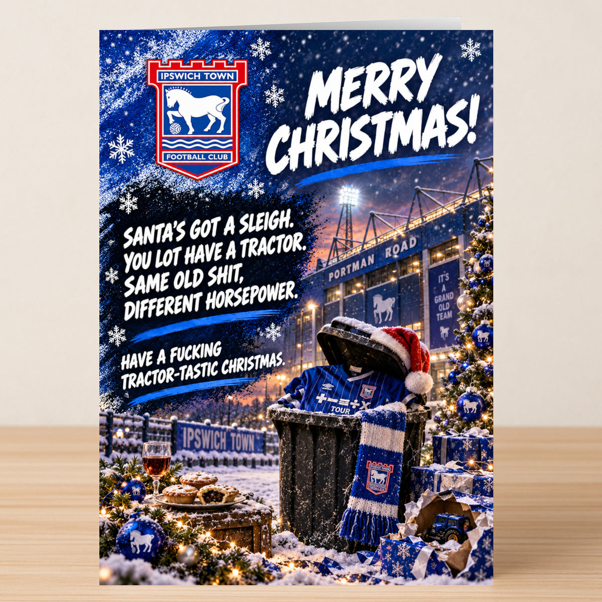 Ipswich Town – Funny Christmas Card featuring the team logo, a stadium backdrop, and the text: “Merry Christmas! Santa’s got a sleigh. You lot have a tractor. Same old shit, different horsepower.”