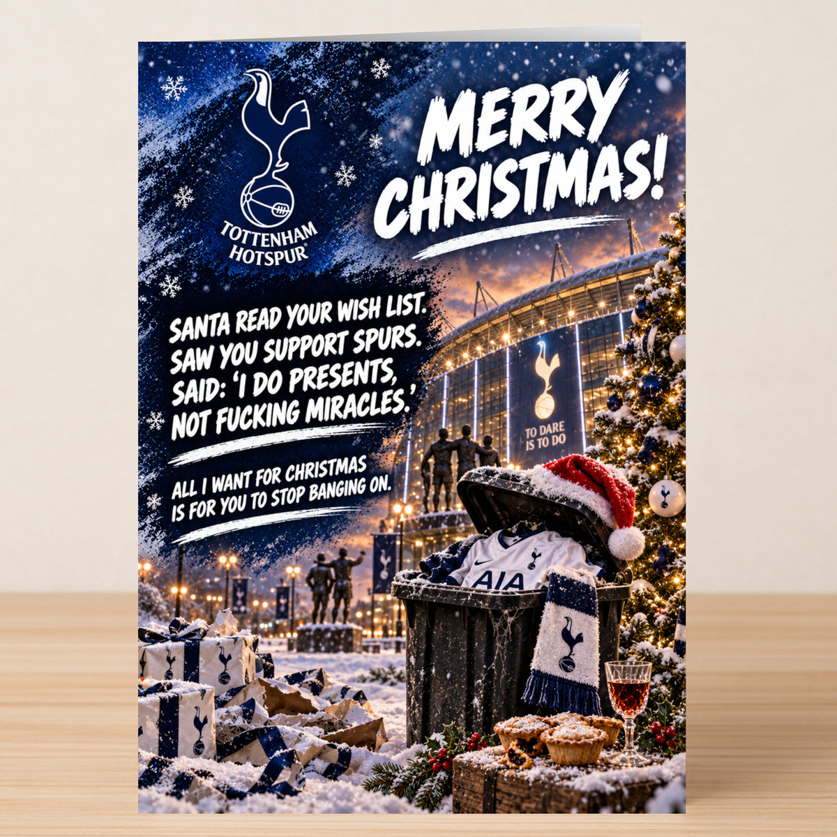 A Twisted Gifts Tottenham Hotspur – Funny Christmas Card featuring a snowy stadium with a Santa hat perched on a trash bin overflowing with team merchandise.