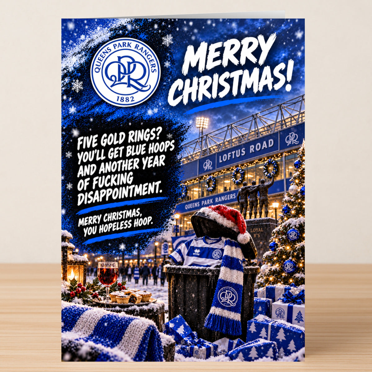 A snowy Queens Park Rangers – Funny Christmas Card featuring a bin wearing a Santa hat and team scarf, with text promising blue hoops and another year of fucking disappointment.