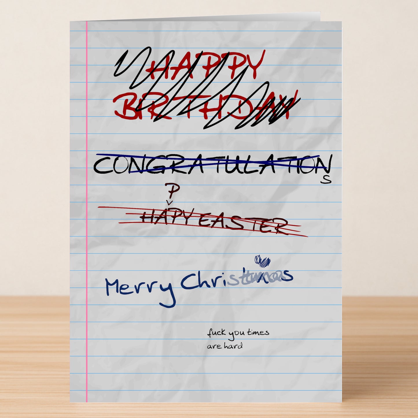 The Hard Times Xmas Funny Christmas Card by Twisted Gifts features crossed-out greetings like "Happy Birthday" and "Congratulations," replaced with "Merry Christmas." Small print below reads, “fuck you times are hard”—a cheeky twist on festive cheer.