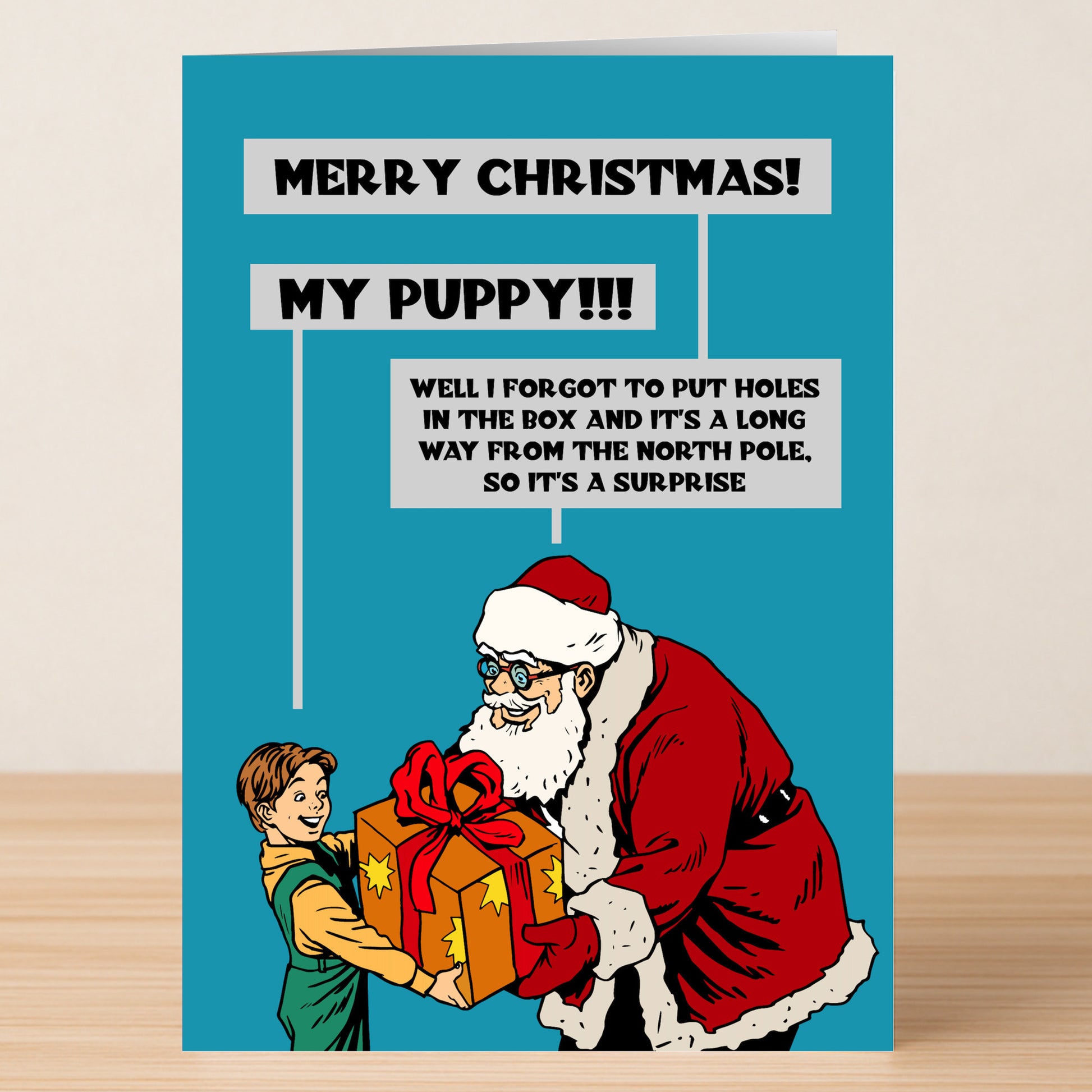The Puppy Funny Christmas Card by Twisted Gifts features a cartoon Santa giving a gift to a happy child, with speech bubbles: "Merry Christmas! My puppy!!!" and "I forgot to put holes in the box, so it's a surprise." Perfect for dog lovers!.
