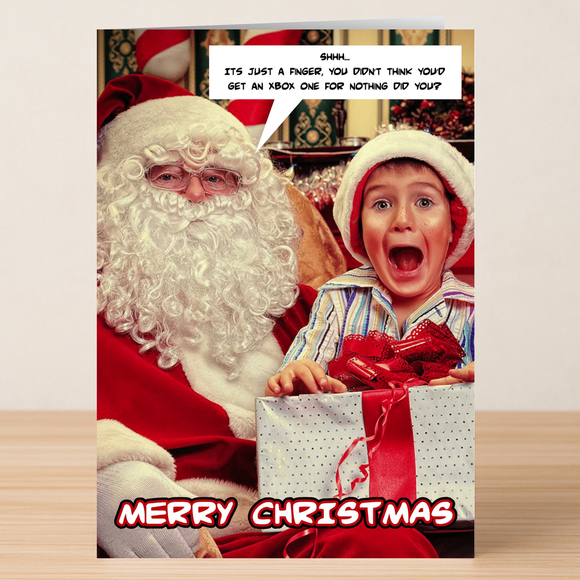 A child in a Santa hat looks shocked as Santa gestures for silence, with a caption joking about not getting an XBox. "Merry Christmas" appears below. This is the XBox Rude Christmas Card by Twisted Gifts!.