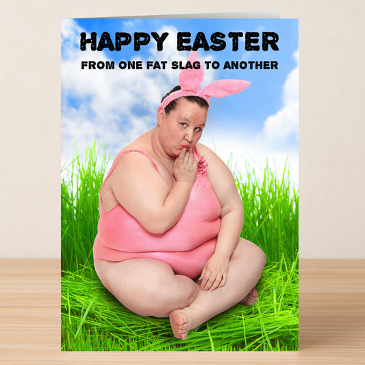 The Fat Slag Insulting Easter Card by Twisted Gifts shows a person in pink with bunny ears on the grass, finger to lips. Text reads: "Happy Easter from one fat slag to another." A humorous, playful card for Easter.