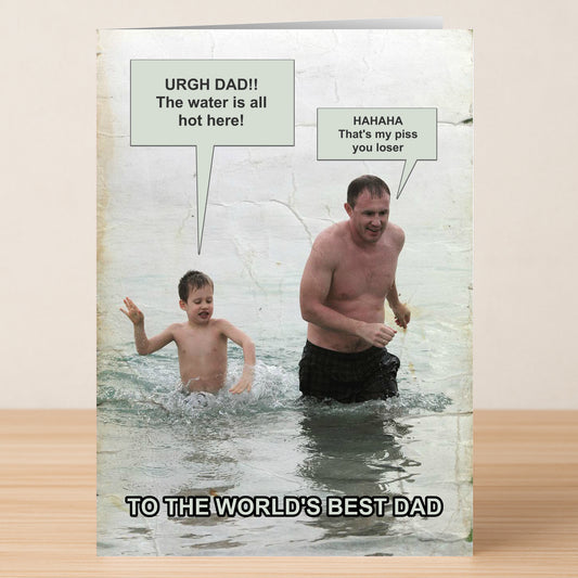 A man and child wade in water; the child complains, and the man jokes. Text: "TO THE WORLD'S BEST DAD." The Hot Water Funny Father's Day Card by Twisted Gifts—perfect for dads who love to make memories (and jokes)!.