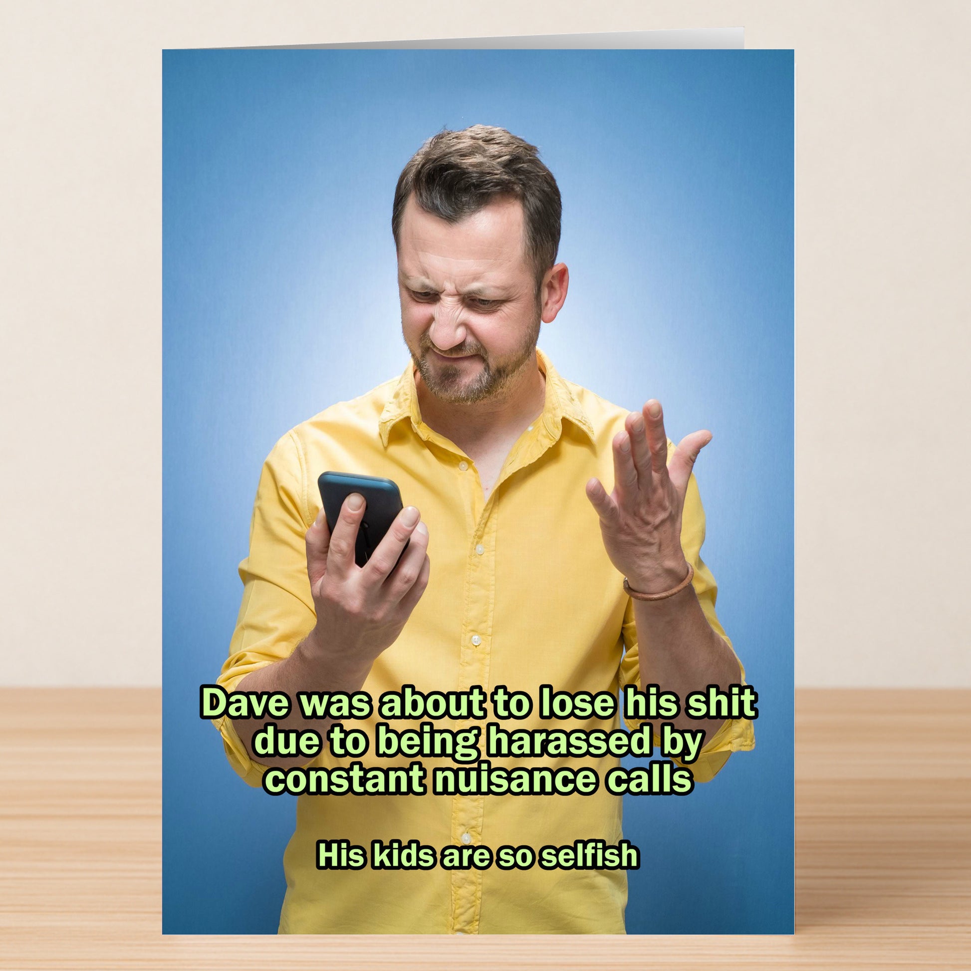 A man in a yellow shirt looks frustrated at his phone, raising one hand; Twisted Gifts’ Selfish Kids Funny Fathers Day Card jokes about getting nuisance calls from selfish kids.
