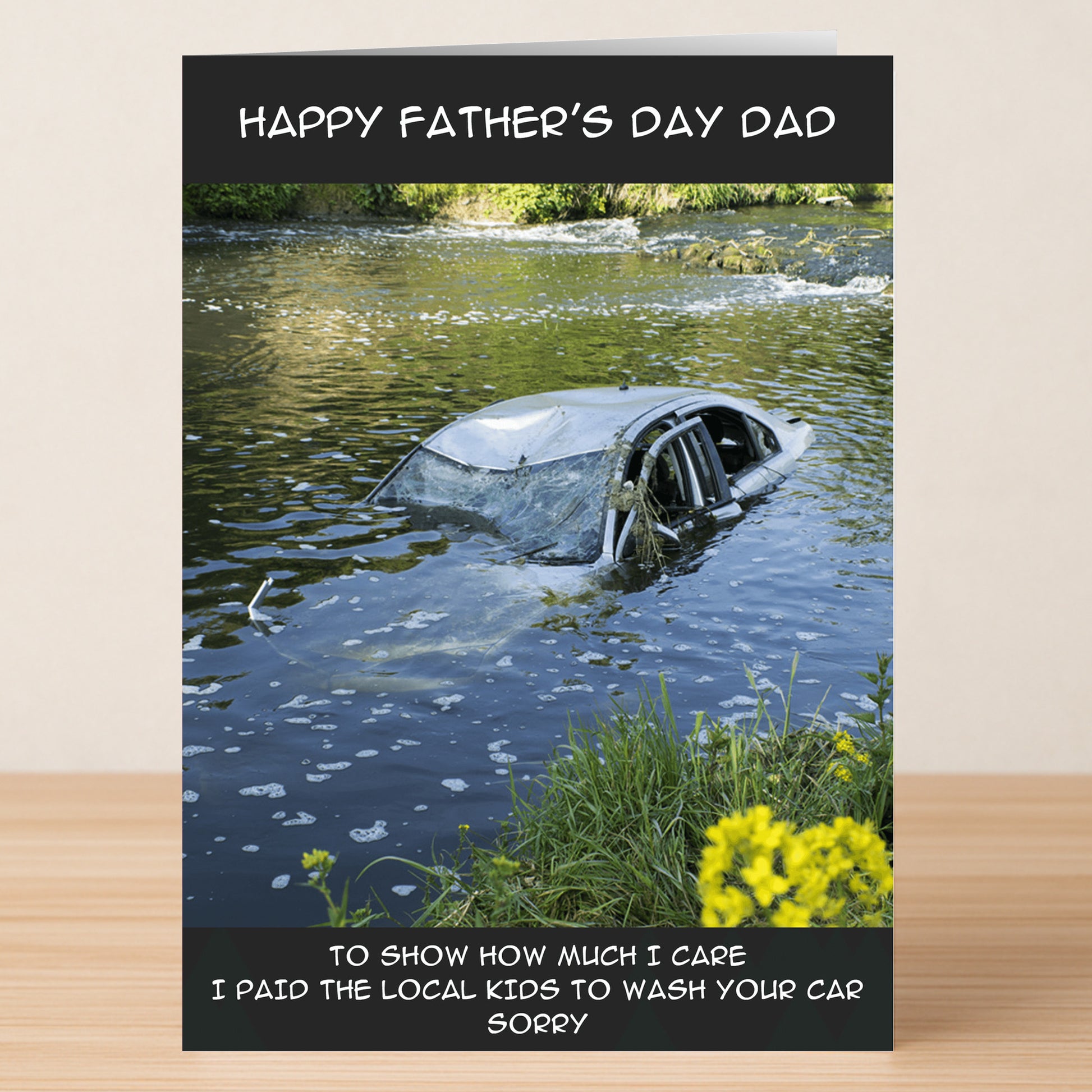The Sorry Funny Father's Day Card by Twisted Gifts shows a car in a river with the message: "Happy Father’s Day Dad" and "To show how much I care I paid the local kids to wash your car. Sorry." Ideal for dad joke lovers!.