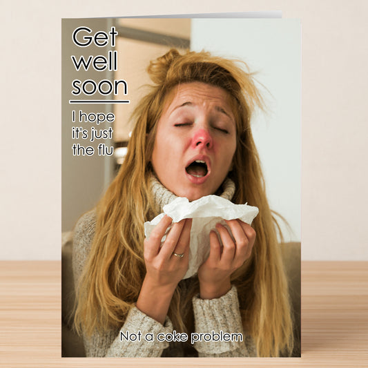 The Just The Flu Funny Get Well Soon Card by Twisted Gifts shows a woman with messy hair and a red nose, holding a tissue and sneezing. The card humorously says, "Get well soon. I hope it's just the flu. Not a coke problem.